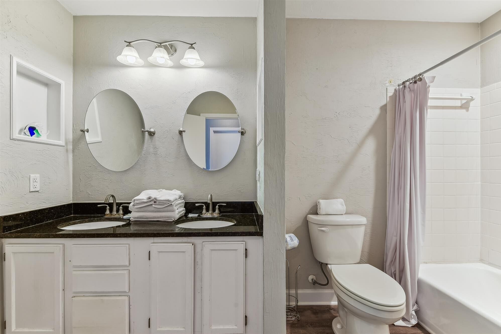 A bathroom with two sinks, a toilet, a bathtub, and a shower curtain.