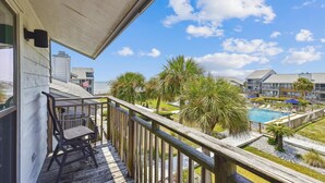A balcony with a view of a swimming pool and palm trees.