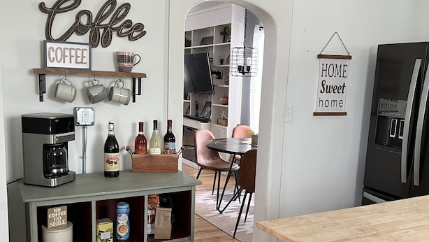 A kitchen with a coffee station, a refrigerator, and a dining area with chairs and a table. - Updated kitchen, Close to downtown, Pet friendly, Privacy fenced backyard! (Kearney)