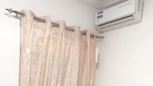 A bedroom with a bed, a television on a stand, and an air conditioning unit on the wall. - Freedom 2 furnished room (Dakar)