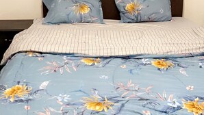 A bedroom with a bed, pillows, and a wall-mounted painting. - Freedom 2 furnished room (Dakar)