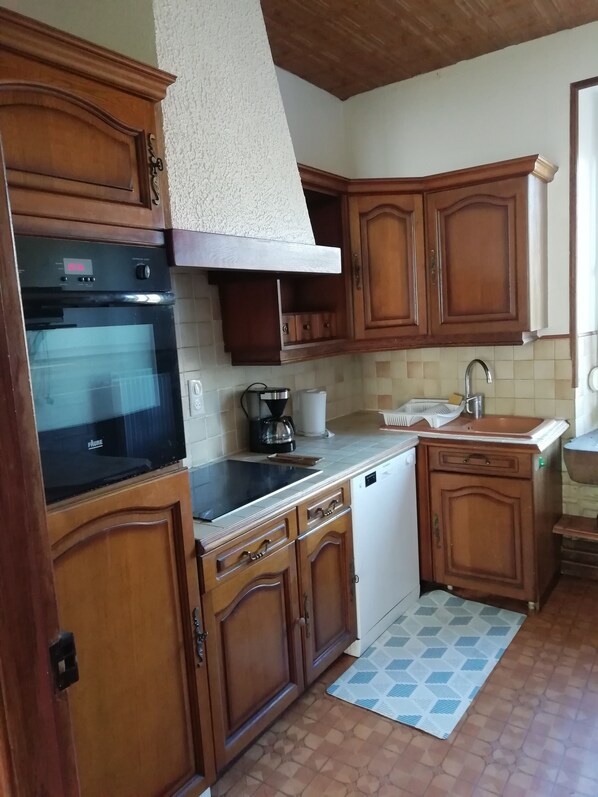 A kitchen with wooden cabinets, a black oven, a coffee maker, and a sink.