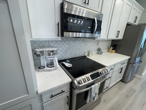 Eine moderne Küche mit integriertem Mikrowellenherd, Kaffeemaschine, Herd, Backofen und einem Edelstahlkühlschrank.
