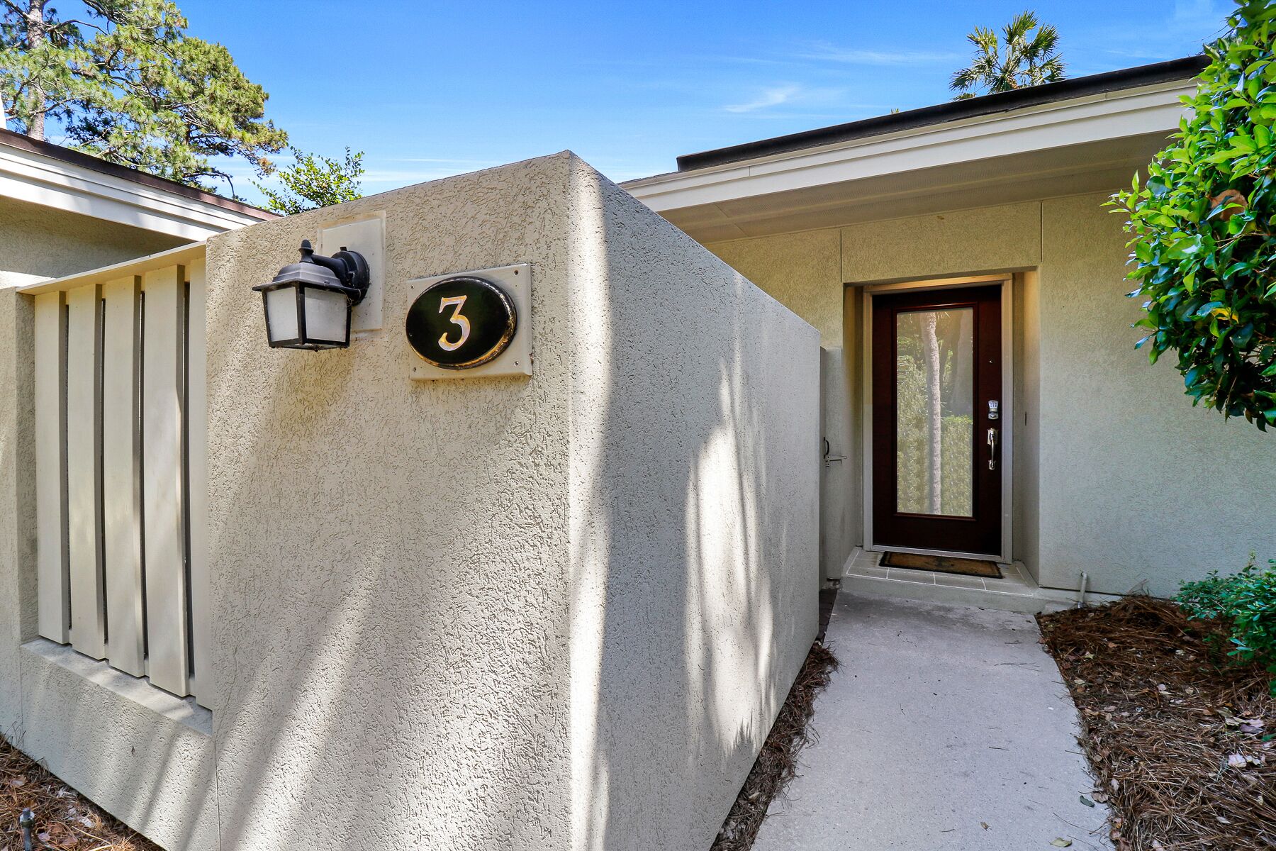 A house with a number 3 sign, a door, and a small porch area.