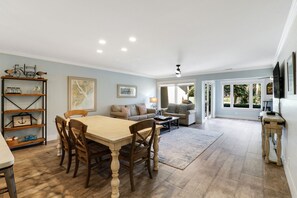 A spacious living area with a dining table, sofas, and a TV.