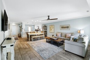 A spacious living room with a dining area, a sofa, and a television.