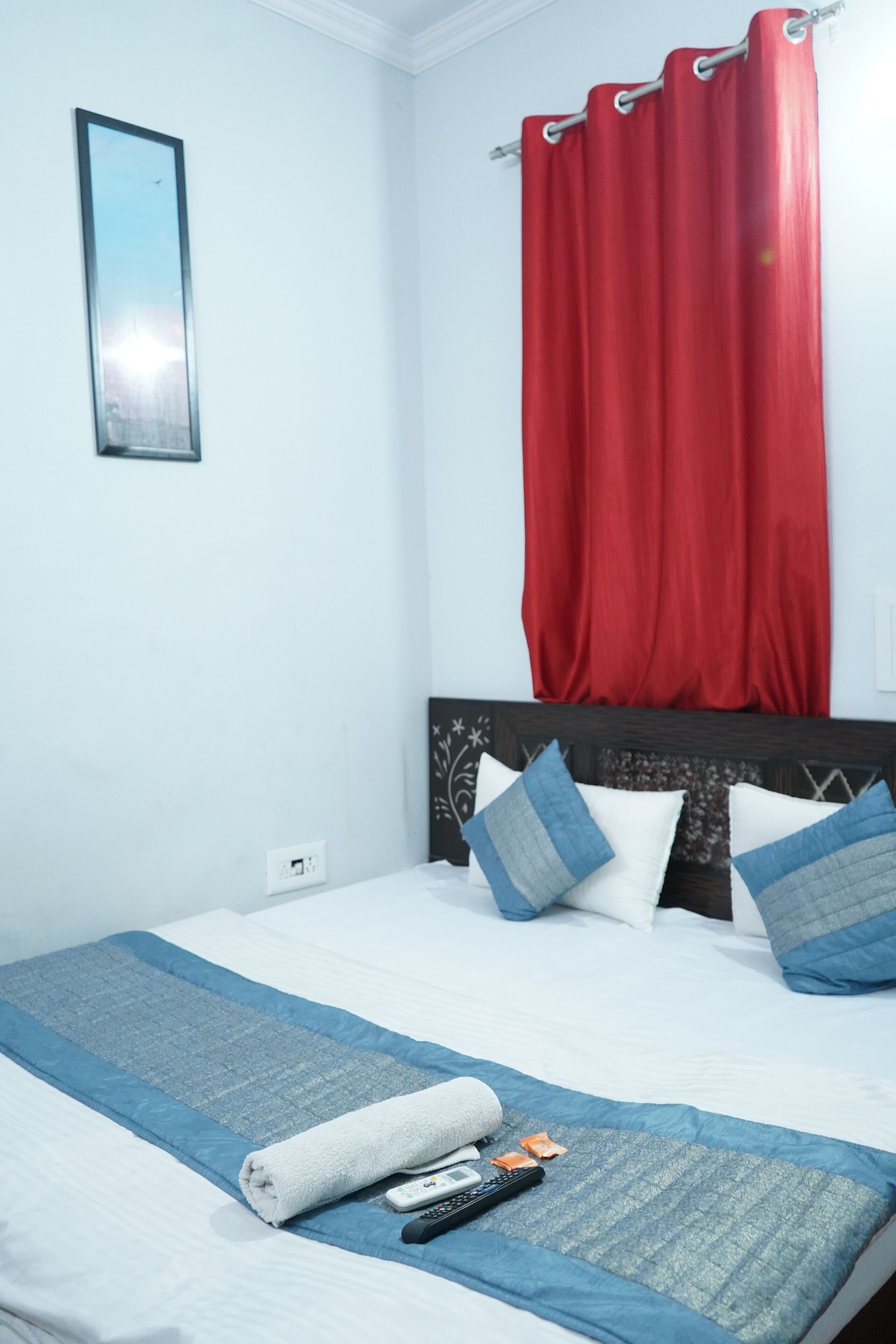 Ein ordentlich bezogenes Bett mit einer blau-weißen Tagesdecke, ein weißes Handtuch und eine Fernbedienung auf dem Bett.