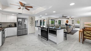 A modern kitchen with a central island, built-in appliances, and a dining area with a sofa and chairs. - Blue Water is Calling! 5bedroom 3bath with large pool and 150 ft of dockage 2 kayaks included (Marathon)