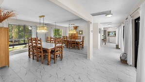A spacious dining area with a high ceiling, large windows, and a view of greenery outside. - Blue Water is Calling! 5bedroom 3bath with large pool and 150 ft of dockage 2 kayaks included (Marathon)