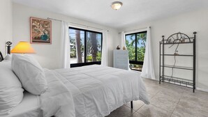 A bedroom with a bed, a nightstand with a lamp, a dresser, and a metal shelf unit. - Blue Water is Calling! 5bedroom 3bath with large pool and 150 ft of dockage 2 kayaks included (Marathon)