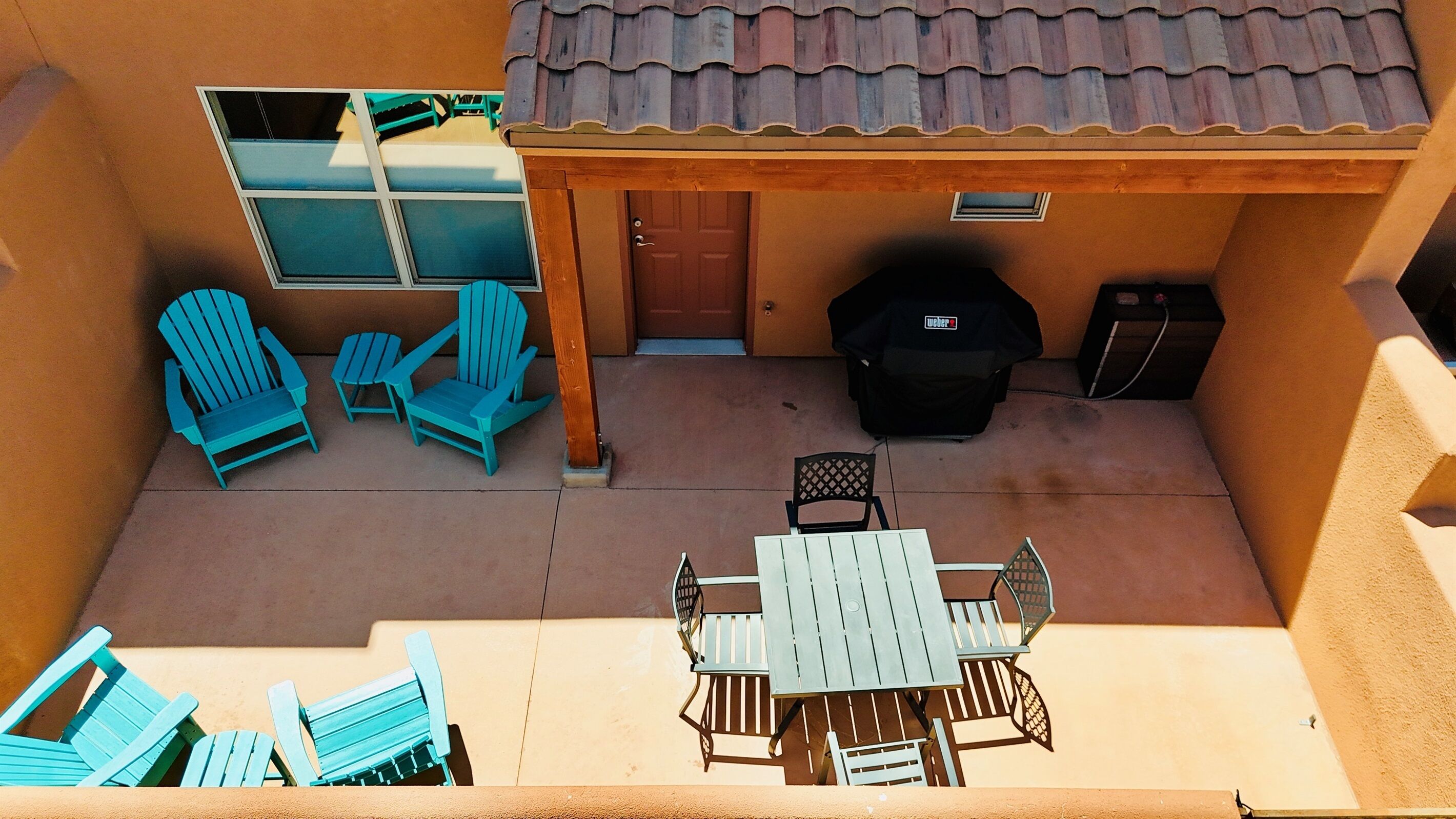 Eine Terrasse mit Tisch und Stühlen, einem Grill und einem überdachten Sitzbereich mit Stühlen.