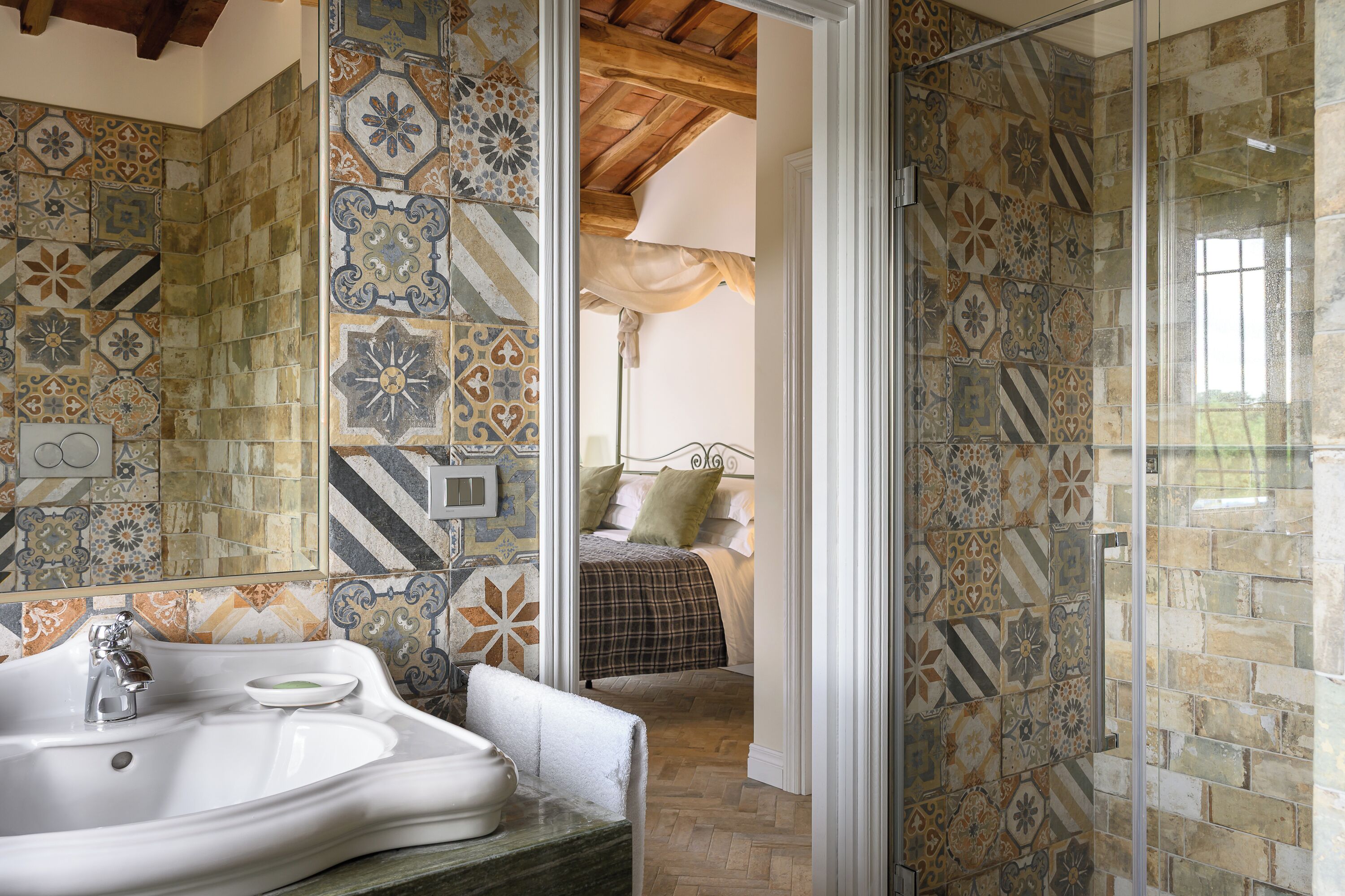 A bathroom with a large bathtub, a sink, and a shower area with patterned tiles.