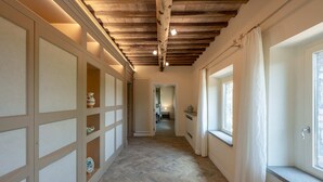 Un pasillo con vigas de madera, suelo de espiga y vistas a una habitación con ventana y radiador.