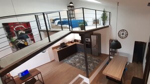 Un appartement moderne de style loft, doté d’une mezzanine, d’un coin cuisine, d’un espace repas et d’un salon.