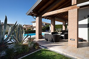 Un patio couvert avec des meubles d’extérieur, une piscine et un jardin agrémenté de plantes d’agave.