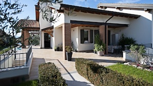 Una casa moderna con un porche cubierto, fachada de ladrillo y un jardín cuidado.