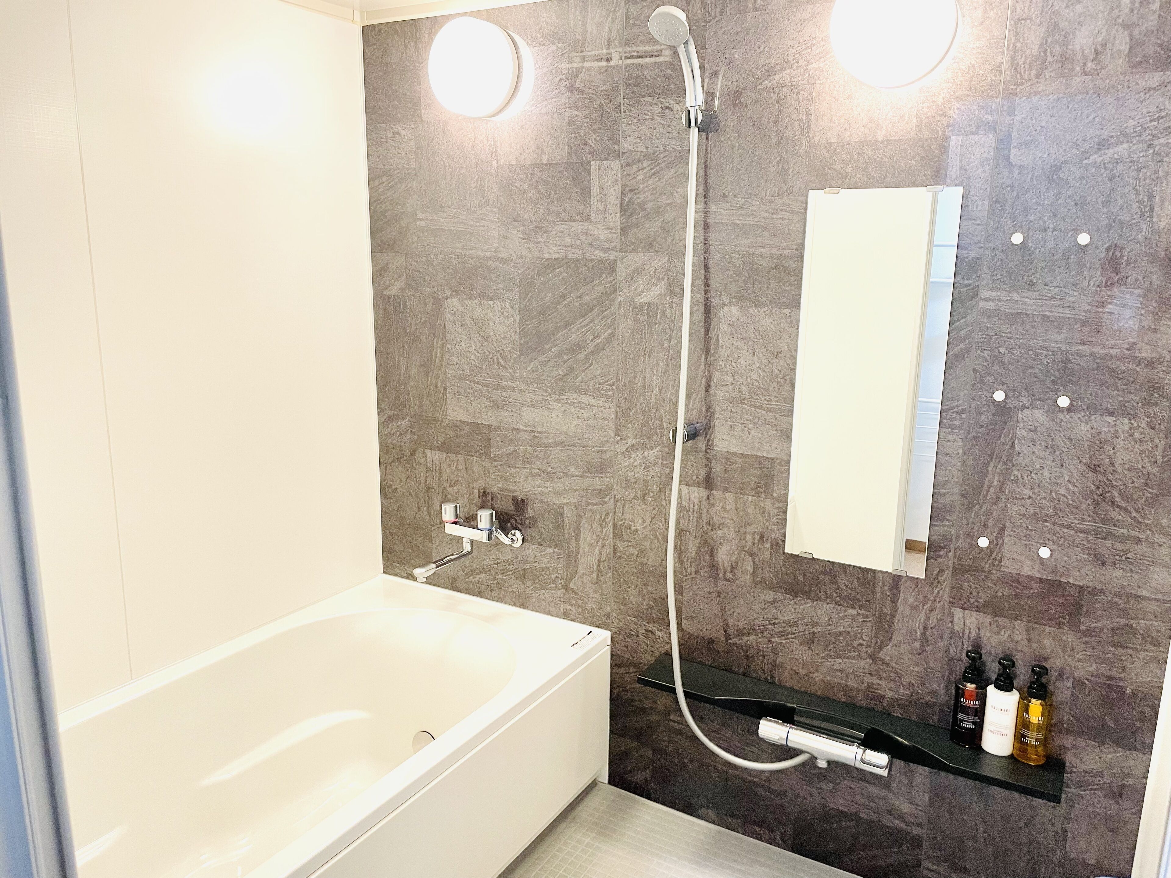 A modern bathroom with a bathtub, a shower, and a mirror.