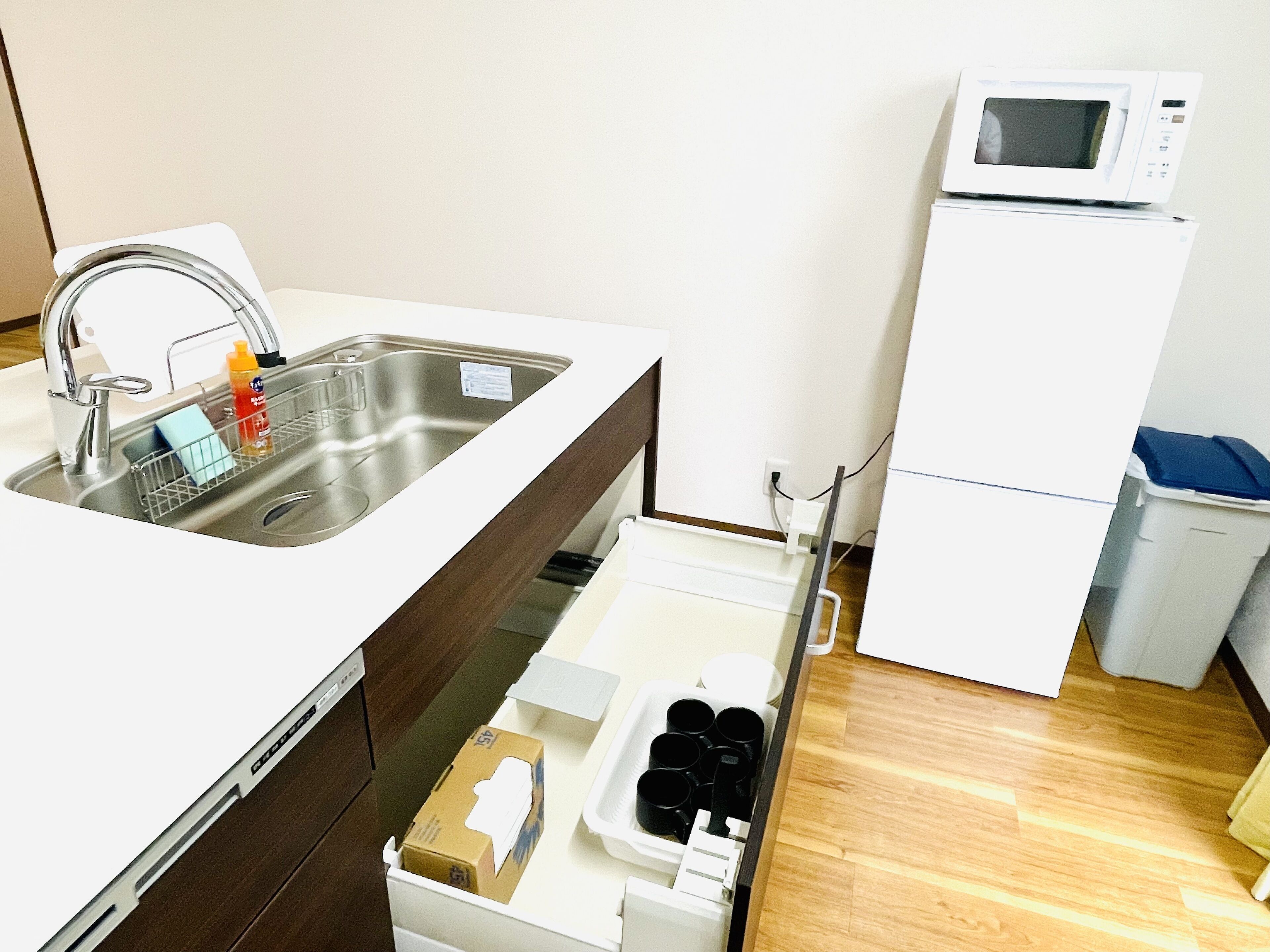 A small kitchenette with a sink, a microwave, and a storage drawer.