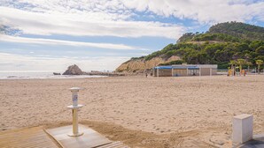 A beach with a volleyball net, a lifeguard tower, and a building with a blue roof. - Apartment 'Beach and Green' with Sea View, Wi-Fi and Air Conditioning (Alicante)