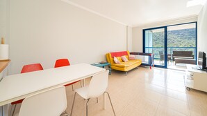 A modern room with a dining table, chairs, a sofa, and a balcony with a view. - Apartment 'Beach and Green' with Sea View, Wi-Fi and Air Conditioning (Alicante)
