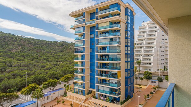 A multi-story building with balconies, a staircase, and a view of a green hillside. - Apartment 'Beach and Green' with Sea View, Wi-Fi and Air Conditioning (Alicante)