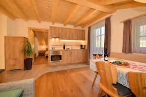 Una cocina moderna con armarios de madera, un comedor con una mesa dispuesta para dos personas y un rincón de estar acogedor.