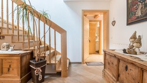 Una scala in legno con una pianta, un settimino di legno e un quadro appeso al muro.