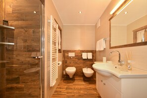 Une salle de bain moderne équipée d’une douche, de toilettes, d’un bidet et d’un lavabo.