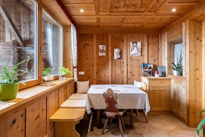 Un intérieur en bois avec une table à manger, des bancs et des plantes en pot.