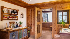 Un interno in legno con una cantinetta, un mobile decorativo e una porta che dà su un'altra stanza.