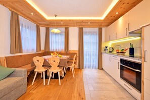 Une cuisine moderne avec des meubles en bois, un four encastré et un coin repas comprenant une table et des chaises.