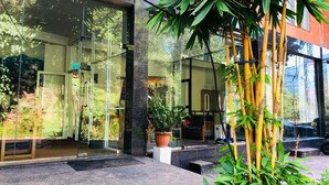 Un edificio moderno con amplios ventanales de vidrio, entrada de concreto y una planta en maceta al frente.