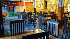 Un restaurante con sillas y mesas de madera, paredes de piedra y un letrero de Coca-Cola.