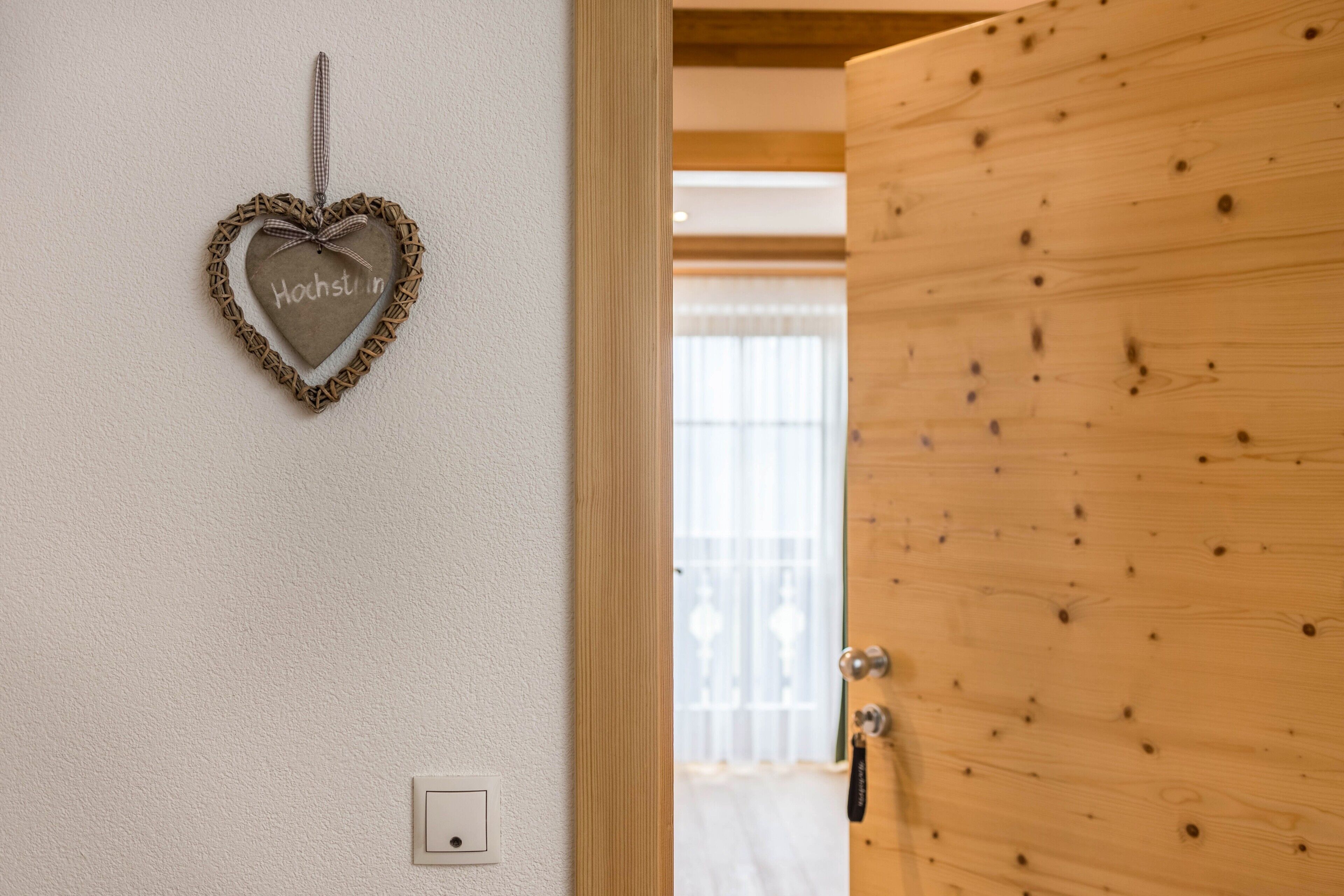 A wooden door with a heart-shaped decoration on the wall.