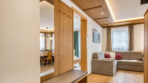 Een moderne woonkamer met een bank, een zitbank, houten vloer en een zichtbare eethoek door een open deur.