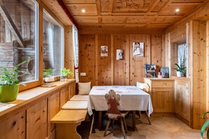 A wooden interior with a dining table, benches, and potted plants.