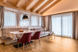 Un accogliente soggiorno con soffitto in legno, un tavolo da pranzo con tovaglia decorata, un divano con cuscini e un piccolo tavolino.
