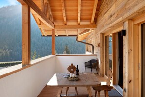 Ein Holzbalkon mit Tisch, Stühlen und einer Flasche.