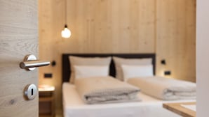 Une pièce aux murs lambrissés, comprenant un lit, une table de chevet et un luminaire suspendu.