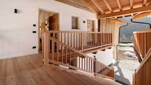 Un intérieur en bois avec un escalier, des murs blancs et une vue sur un paysage montagneux.