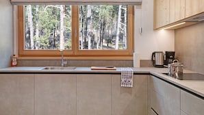 Une cuisine dotée d’une grande fenêtre, d’un évier et d’armoires en bois.