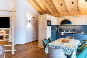 A modern kitchen with wooden cabinets, a built-in microwave, and a dining area with a table set for two.