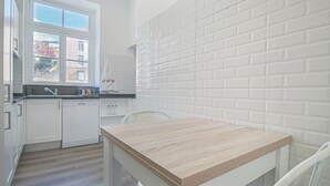 A kitchen with white cabinets, a wooden countertop, and a window with a view of buildings.