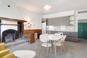 A modern kitchen with a dining area, a fireplace, and a green door. - Workation Castle: Casa Galbiga (Carlazzo)