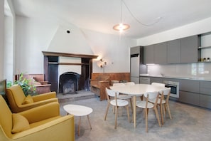 A modern kitchen with grey cabinets, a white dining table with wooden chairs, a fireplace, and a yellow sofa. - Workation Castle: Casa Galbiga (Carlazzo)