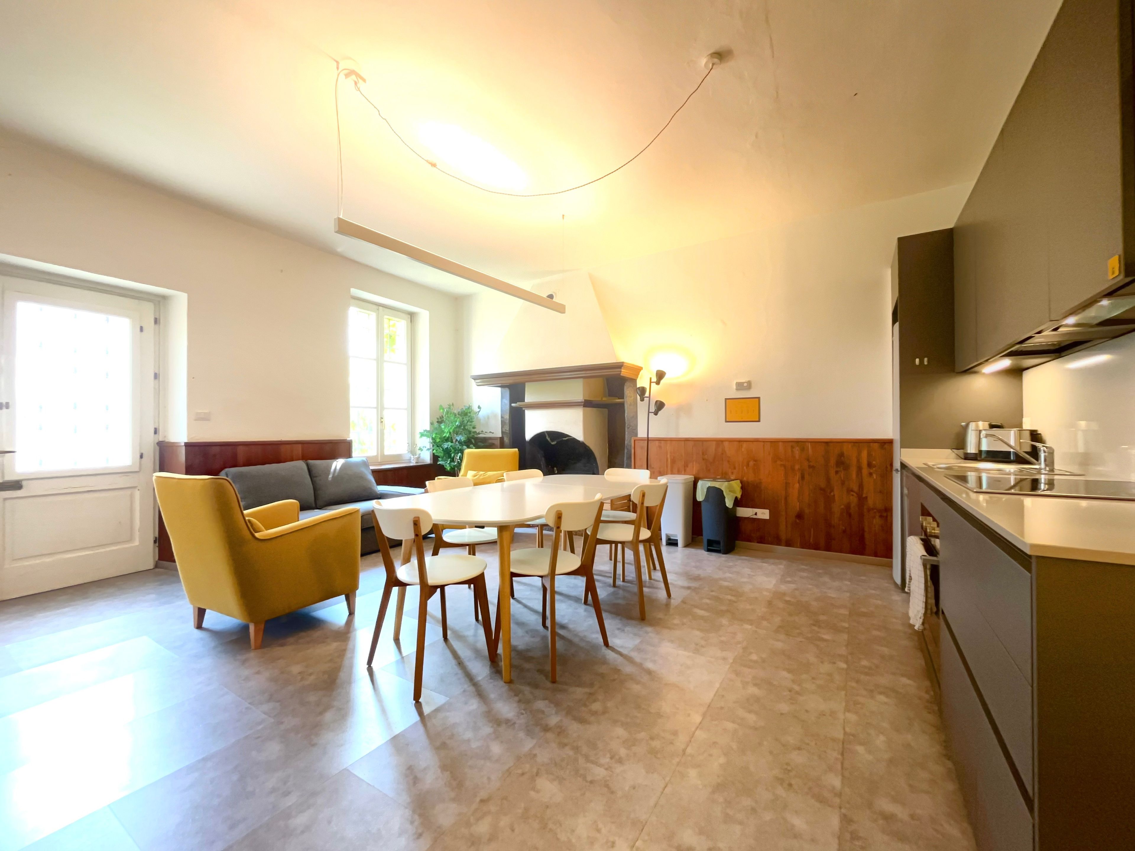A modern kitchen with a dining area, a sofa, and a fireplace.