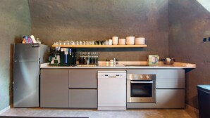 Een praktische keuken met een koelkast, vaatwasser, oven en een koffiehoek.