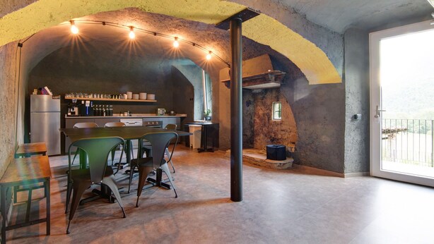 Een ruime keuken met een bar, een eettafel met stoelen en een groot raam voor natuurlijk licht.