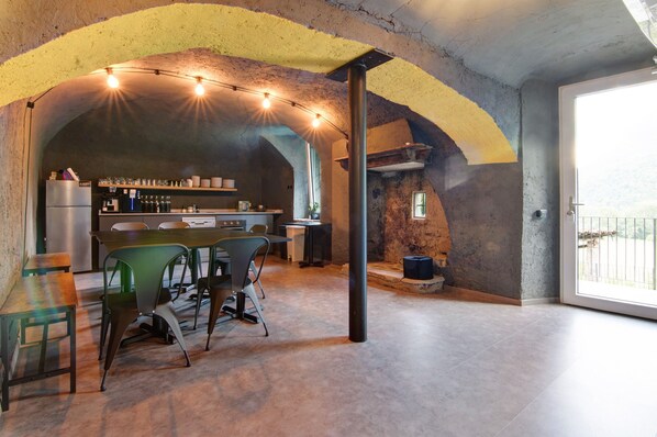 A spacious kitchen with a bar area, a dining table with chairs, and a large window providing natural light. - Workation Castle: Casa Galbiga & Casa Tremezzo (Carlazzo)
