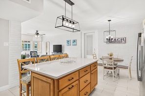 A modern kitchen with a central island, wooden cabinets, and a dining area with a table and chairs.